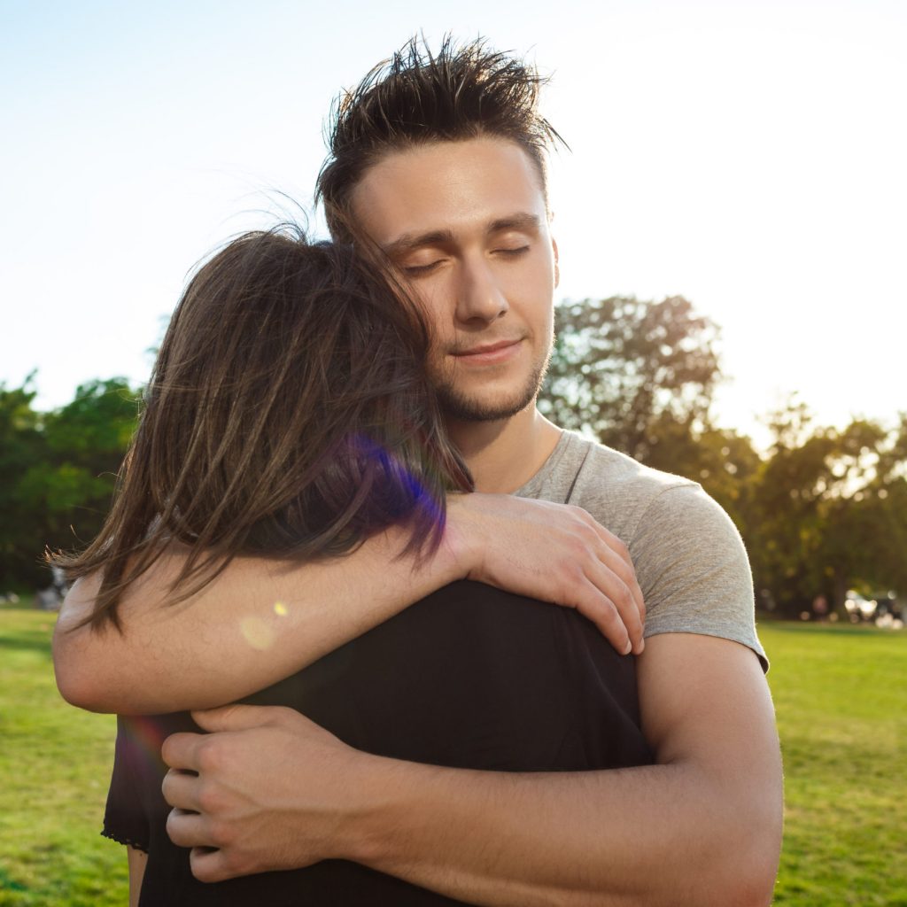 Portrait of young beautiful couple smiling, relaxing, embracing  in park.